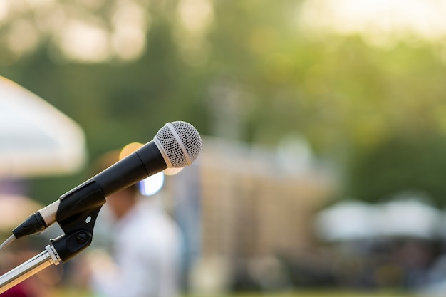 Microphone on the stage over the Abstract blurred photo of green tree with sunset light background, 