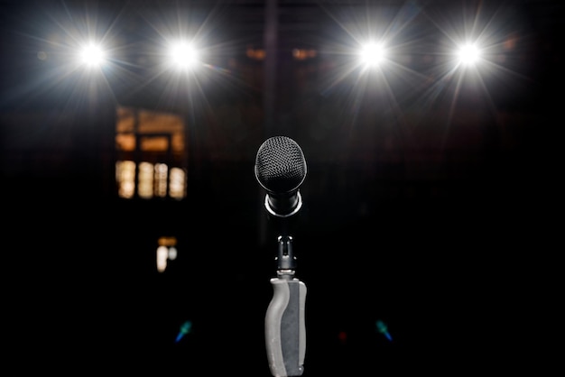 Microphone on the stand with hand nozzle in the center tage with beautiful bokeh spotlights in the background. High quality photo