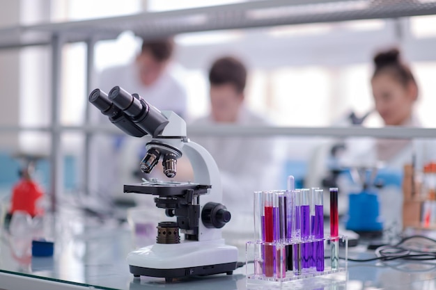 Microscope on the workplace near test tubes with different liquid. Healthcare and biotechnology concept