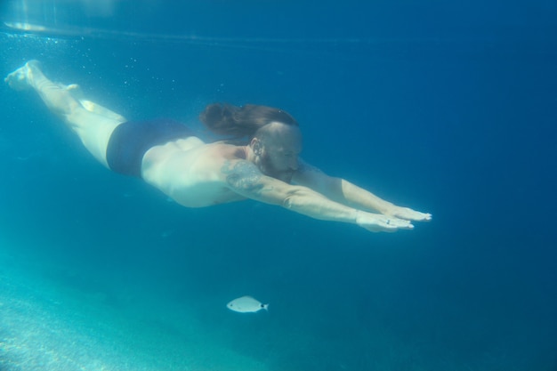 Mid adult bearded long hair man swimming underwater in mediterranean adriatic sea in Croatia