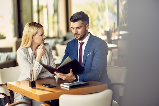 Mid adult couple talking while reading a menu in a restaurant