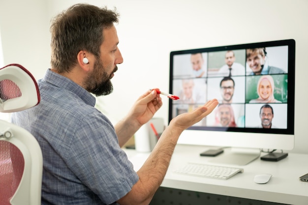 Mid adult man having online conference working from home