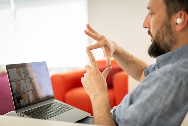 Mid adult man having online conference working from home