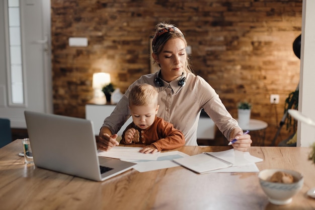 Mid adult mother babysitting her small son while working at home