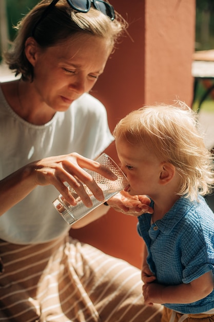 Mid adult woman giving water to her daughter