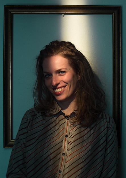 Photo mid adult woman standing against picture frame on wall