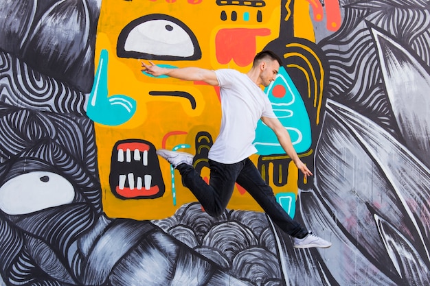 Mid-air shot of handsome man against graffiti wall