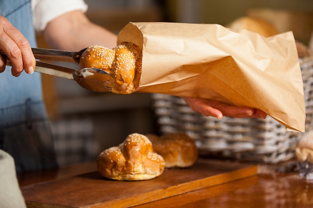 Mid-section of female staff packing sweet food in paper bag