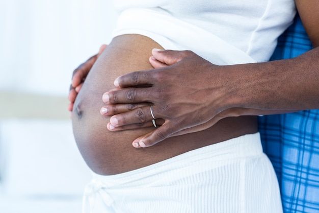 Mid section of husband touching belly of pregnant wife 