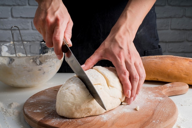 Mid shot baker slicing dough