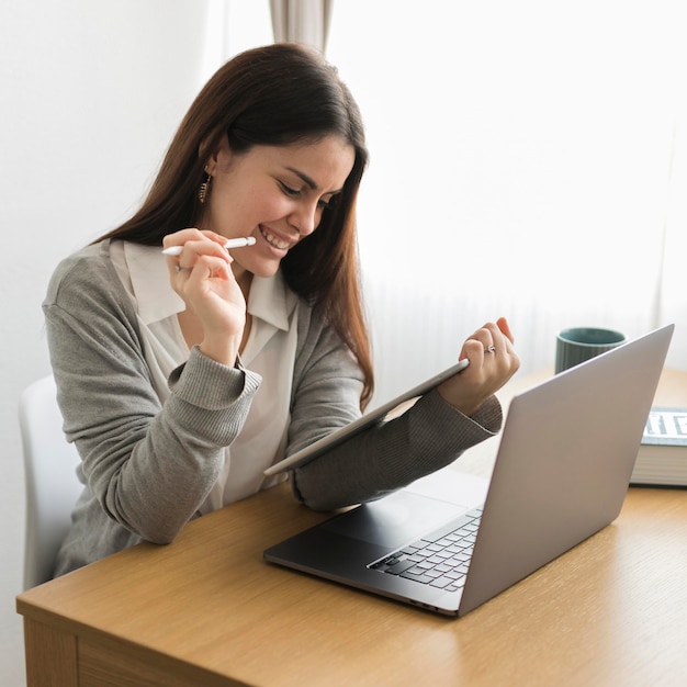 Mid shot brunette woman working at home on tablet