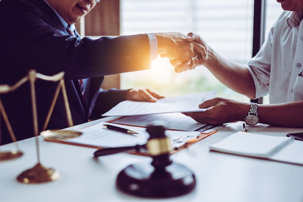 Middle age Asian partner lawyers attorneys shaking hands after discussing a contract agreement done.