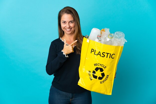 Middle age Brazilian woman holding a bag full of plastic bottles