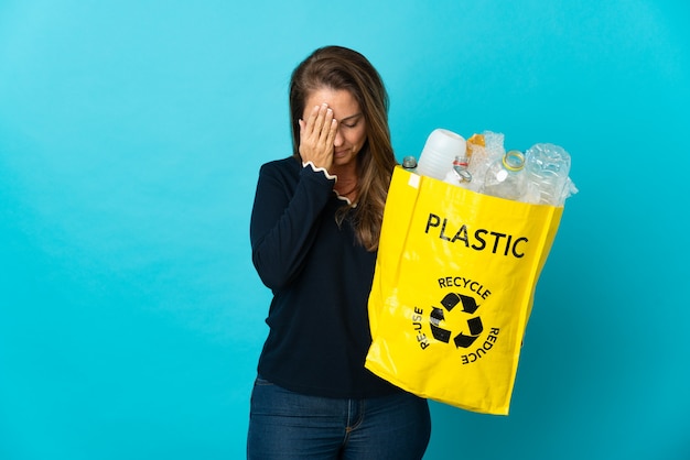 Middle age Brazilian woman holding a bag full of plastic bottles