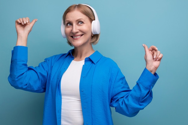 Middle age business concept s woman with headphones without wire dancing on blue background copy