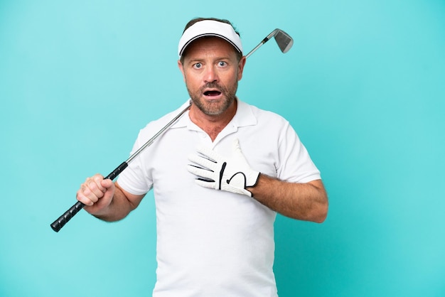 Middle age caucasian golfer player man isolated on blue background surprised and shocked while looking right