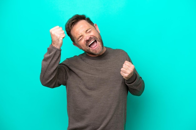 Middle age caucasian man isolated on blue background celebrating a victory