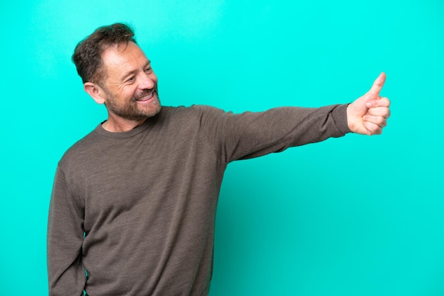 Middle age caucasian man isolated on blue background giving a thumbs up gesture