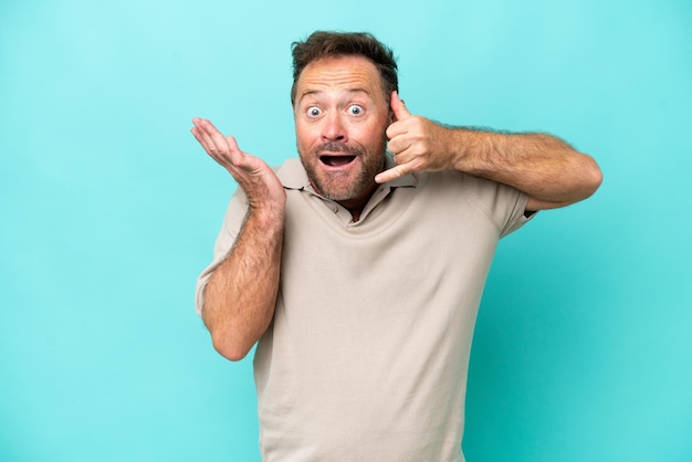 Middle age caucasian man isolated on blue background making phone gesture and doubting