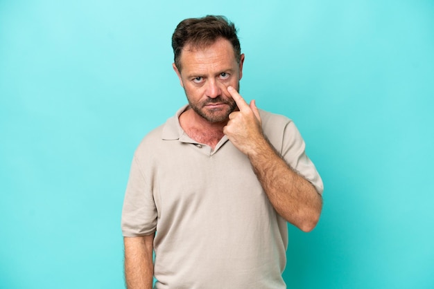 Middle age caucasian man isolated on blue background showing something