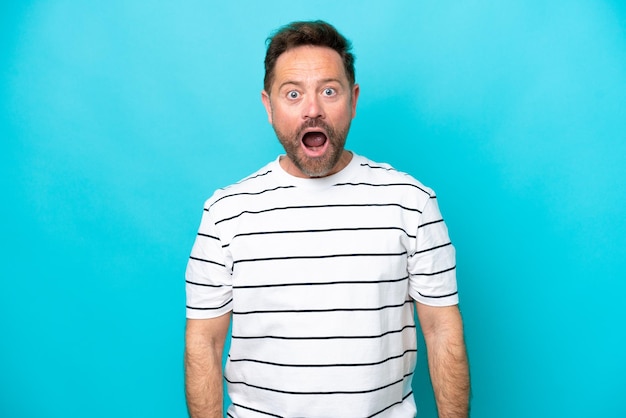 Middle age caucasian man isolated on blue background with surprise facial expression