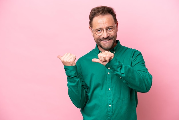 Middle age caucasian man isolated on pink background pointing to the side to present a product