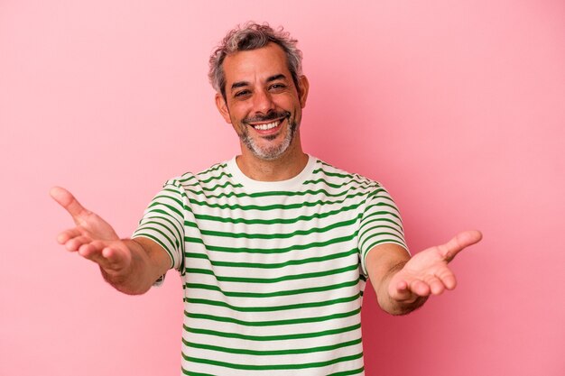 Middle age caucasian man isolated on pink background  showing a welcome expression.