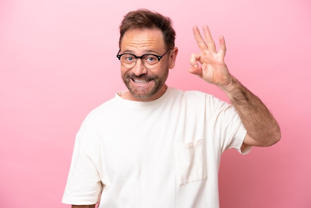 Middle age caucasian man isolated on pink background With glasses and doing OK sign