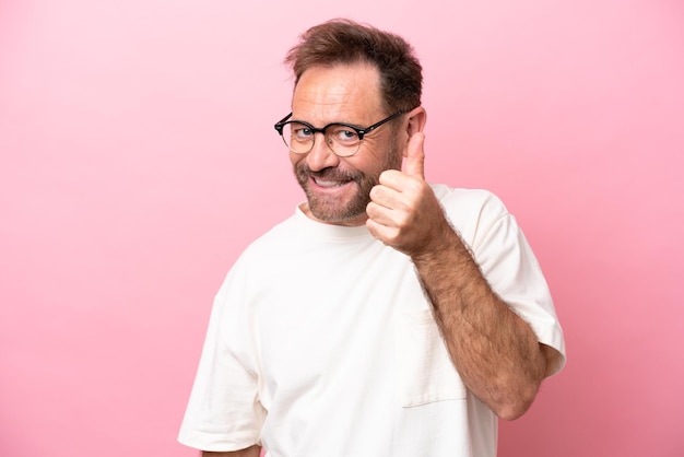 Middle age caucasian man isolated on pink background With glasses and with thumb up