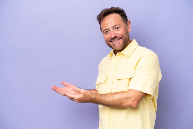 Middle age caucasian man isolated on purple background extending hands to the side for inviting to come