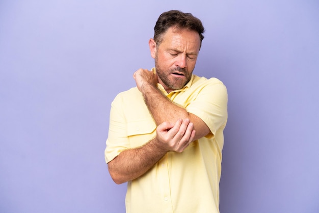 Middle age caucasian man isolated on purple background with pain in elbow