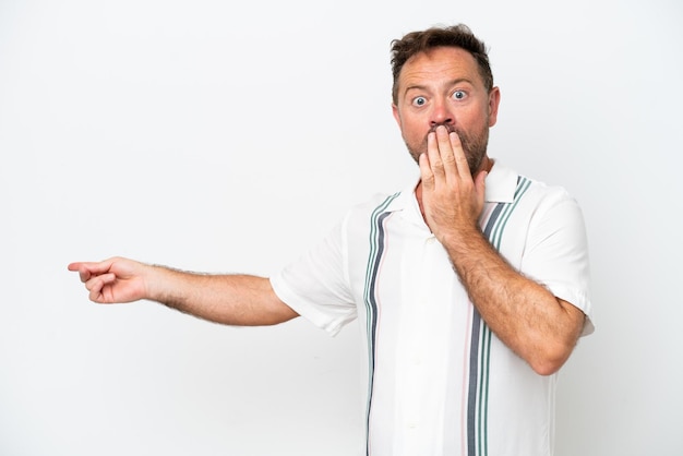 Middle age caucasian man isolated on white background with surprise expression while pointing side