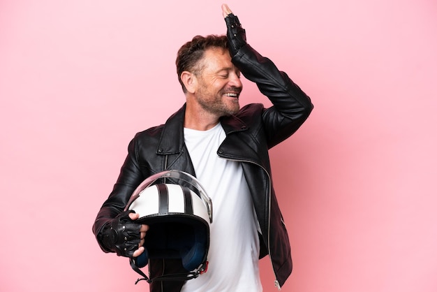 Photo middle age caucasian man with a motorcycle helmet isolated on pink background has realized something and intending the solution