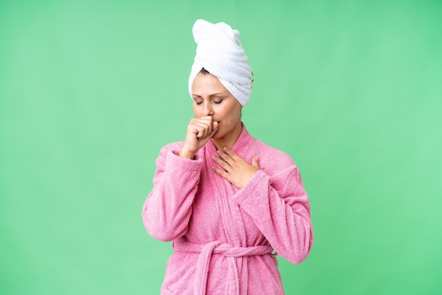 Middle age caucasian woman in a bathrobe over isolated background is suffering with cough and feeling bad