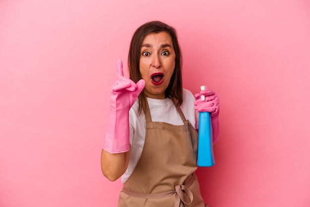 Middle age caucasian woman cleaning home isolated on pink background having an idea, inspiration concept.