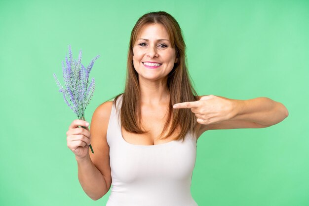 Middle age caucasian woman holding lavender over isolated background and pointing it