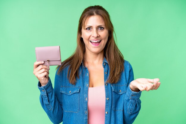 Middle age caucasian woman holding wallet over isolated background with shocked facial expression