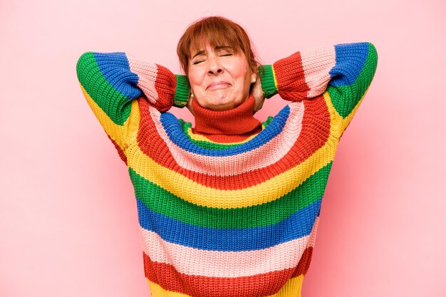 Middle age caucasian woman isolated on pink background feeling confident with hands behind the head