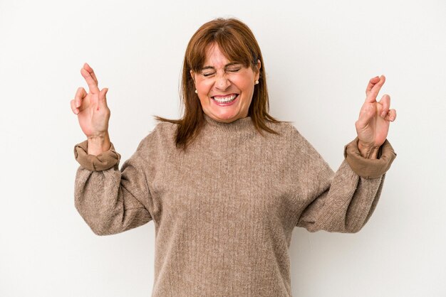 Photo middle age caucasian woman isolated on white background crossing fingers for having luck