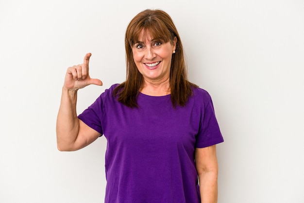 Middle age caucasian woman isolated on white background holding something little with forefingers, smiling and confident.