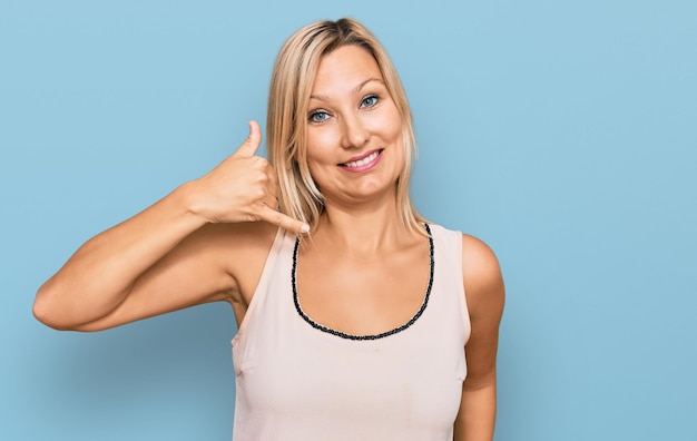 Middle age caucasian woman wearing casual clothes smiling doing phone gesture with hand and fingers like talking on the telephone. communicating concepts.