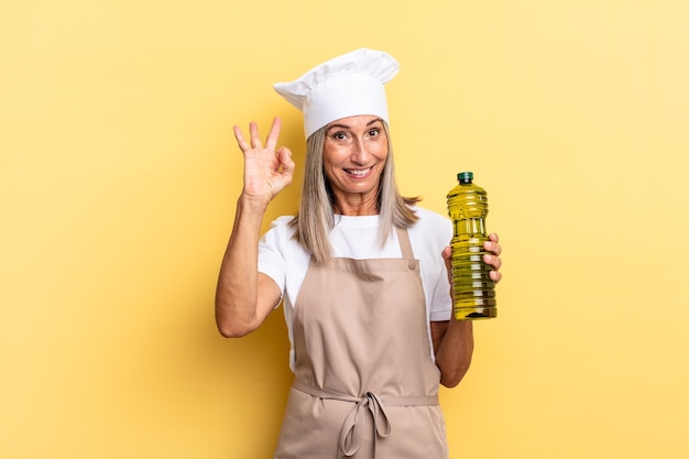 Middle age chef woman feeling happy, relaxed and satisfied, showing approval with okay gesture, smiling