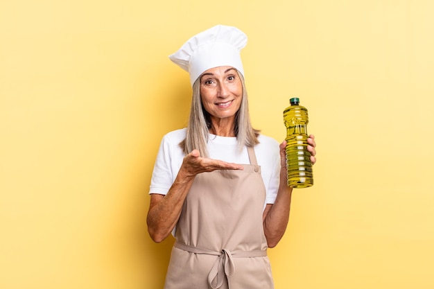 Middle age chef woman smiling cheerfully, feeling happy and showing a concept in copy space with palm of hand