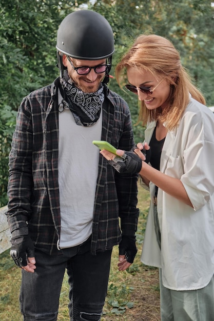 Middle age couple in helmet using mobile phone outdoors travel together