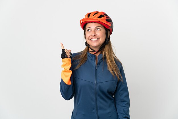 Middle age cyclist woman isolated on white wall pointing up a great idea