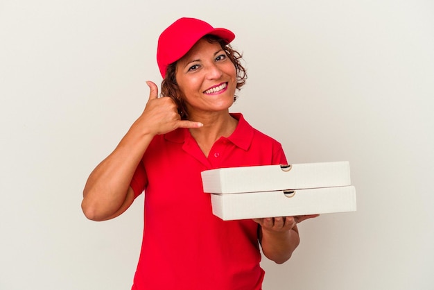 Middle age delivery woman taking pizzas isolated on white background showing a mobile phone call gesture with fingers.