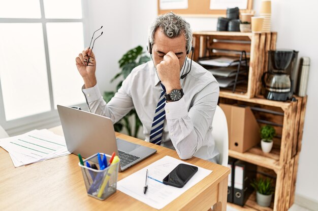 Middle age grey-haired man call center agent stressed working at office