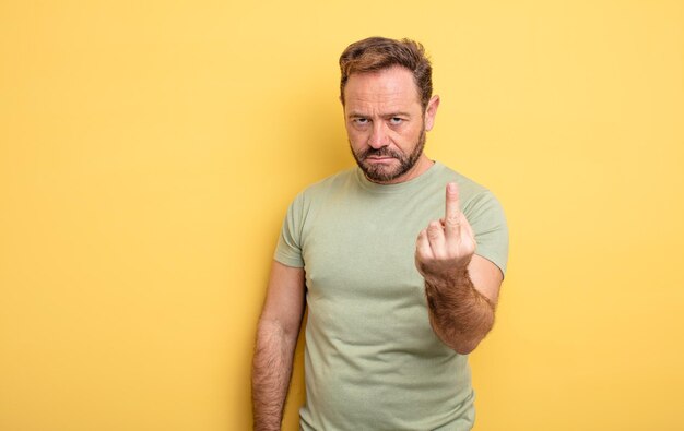 Middle age handsome man feeling angry annoyed rebellious and aggressive flipping the middle finger fighting back