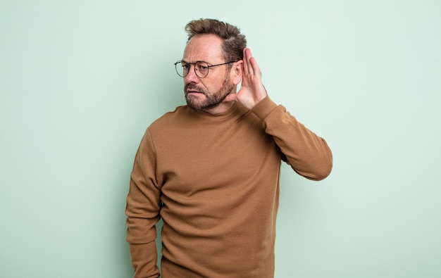 Photo middle age handsome man looking serious and curious, listening, trying to hear a secret conversation or gossip, eavesdropping