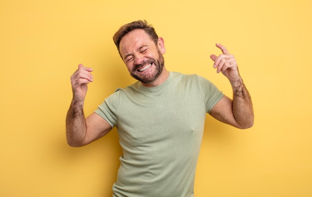 Middle age handsome man smiling, feeling carefree, relaxed and happy, dancing and listening to music, having fun at a party